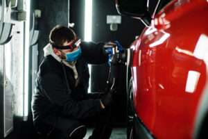 men working on a white automobile for hail damage in a shop denver colorado