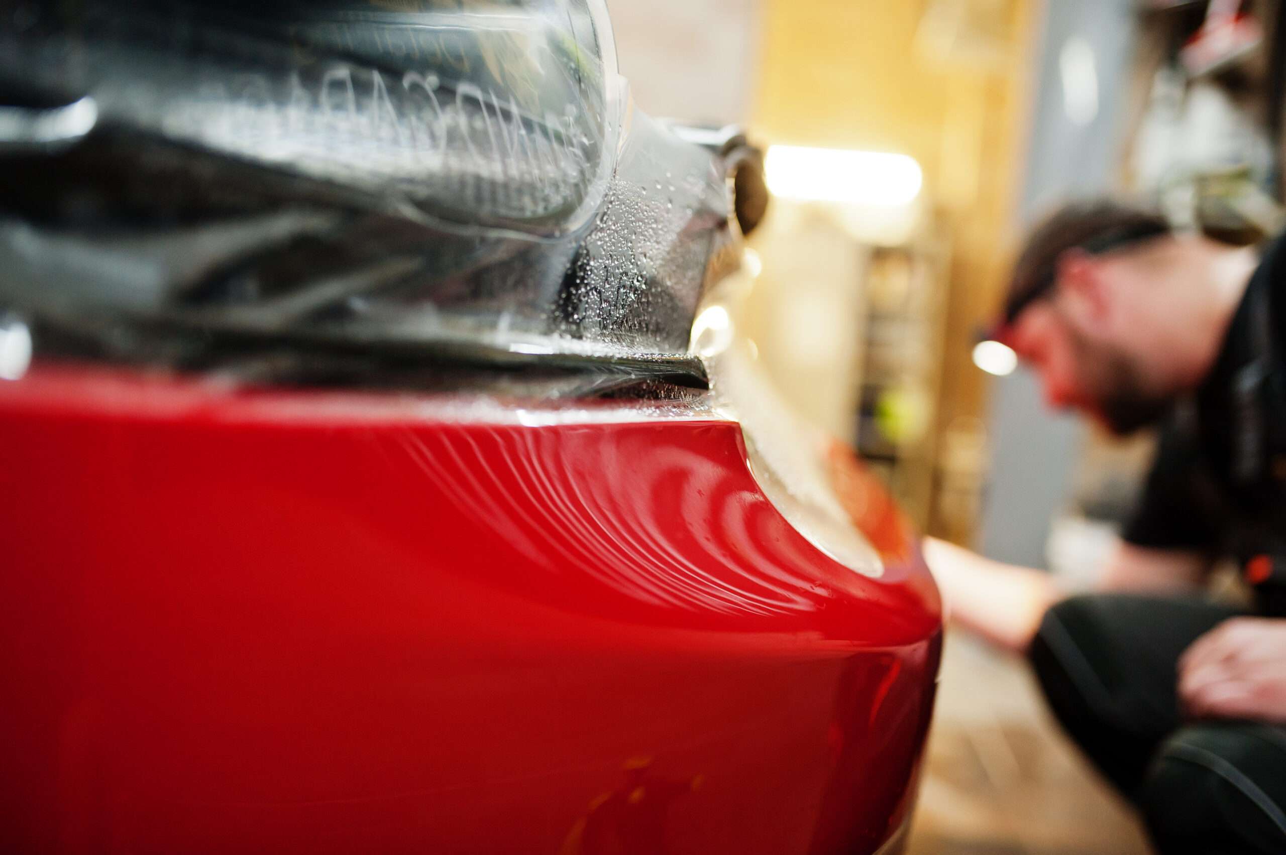 men working on a white automobile for hail damage in a shop denver colorado